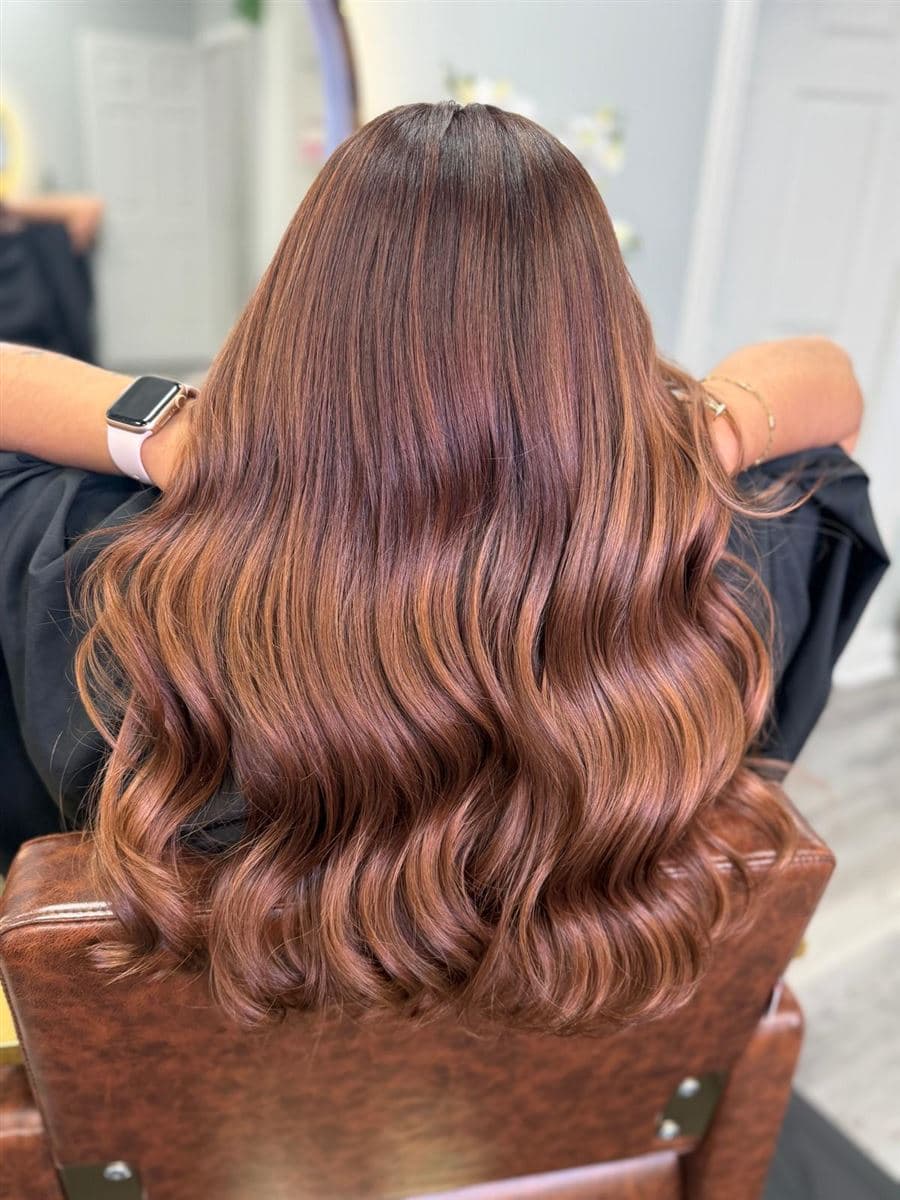 Cabello castaño con reflejos caramelo peinado en ondas suaves, vista desde atrás