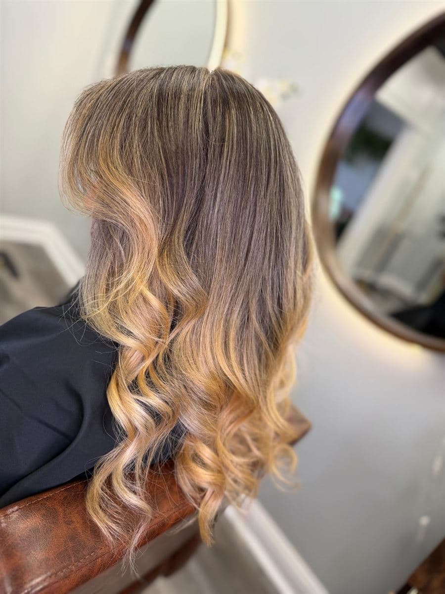 Balayage en tonos rubio miel con raíz difuminada y ondas al agua