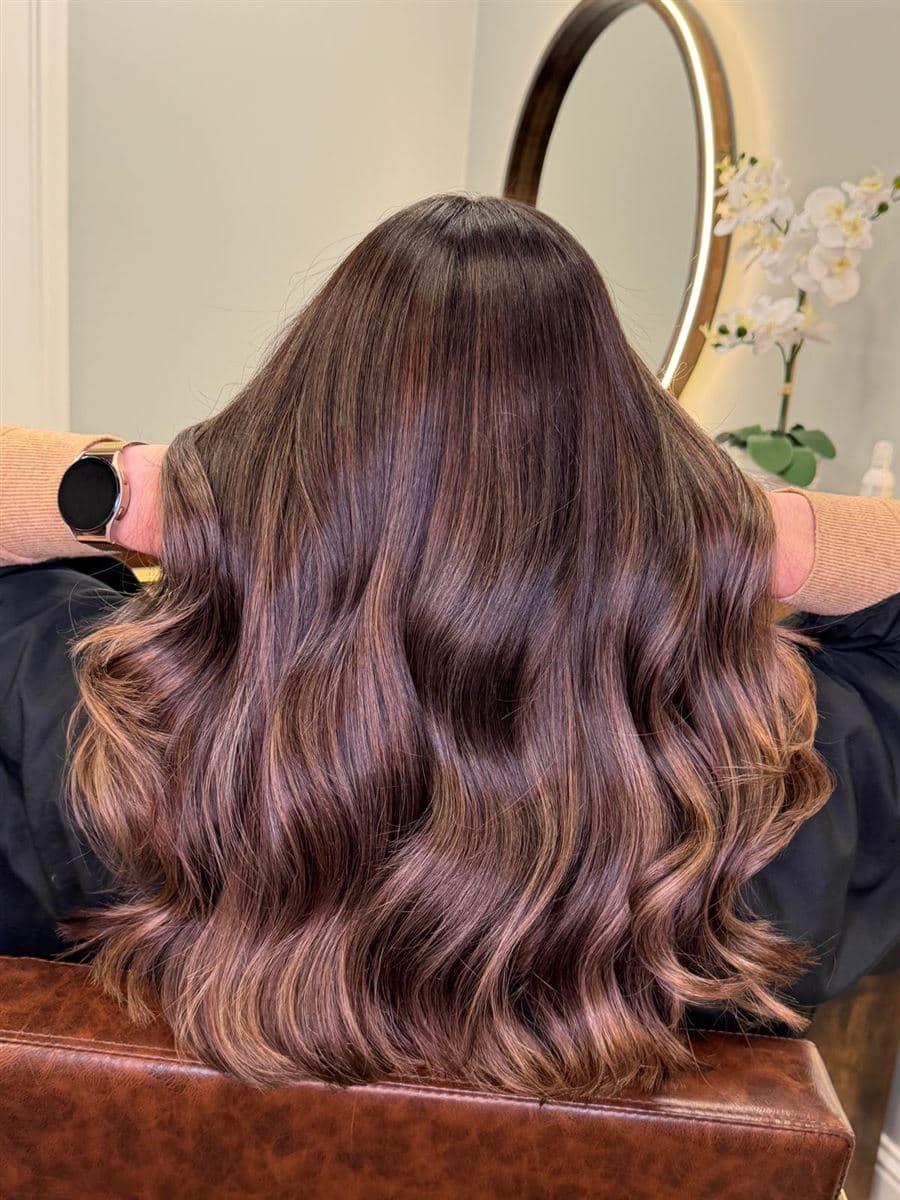 Cabello castaño avellana con balayage y ondas frente al espejo del salón