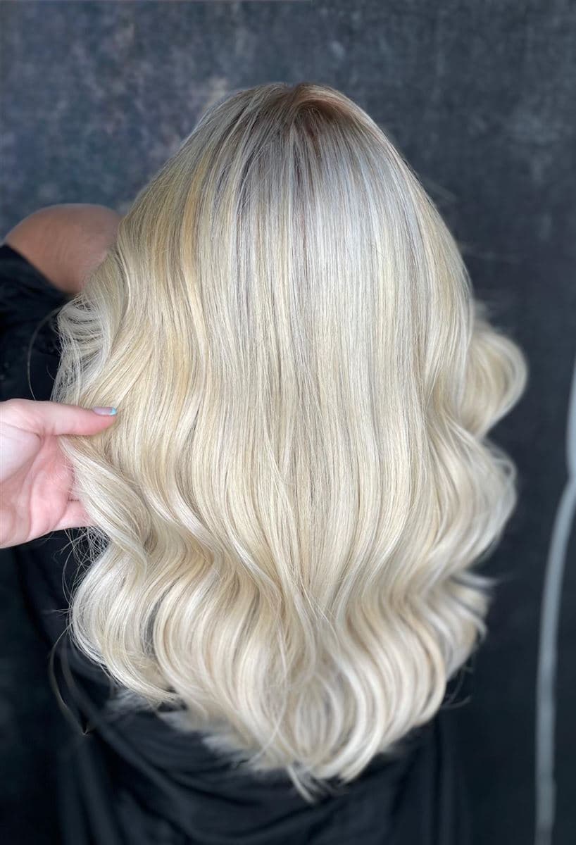 Melena rubio platino con ondas pulidas y raíz sombreada natural