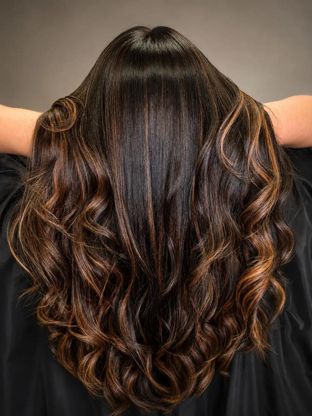Cabello castaño con reflejos caramelo peinado en ondas suaves, vista desde atrás